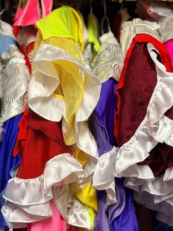 Bunte Kostüme mit weißen Satinrüschen in Rot, Gelb und Lila